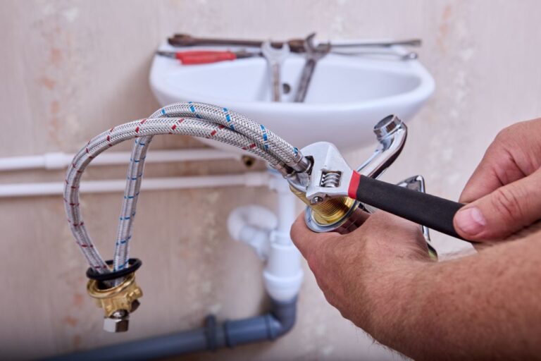 Reparatur eines Waschbeckens mit Zange und Werkzeugsatz vom Hausmeister.